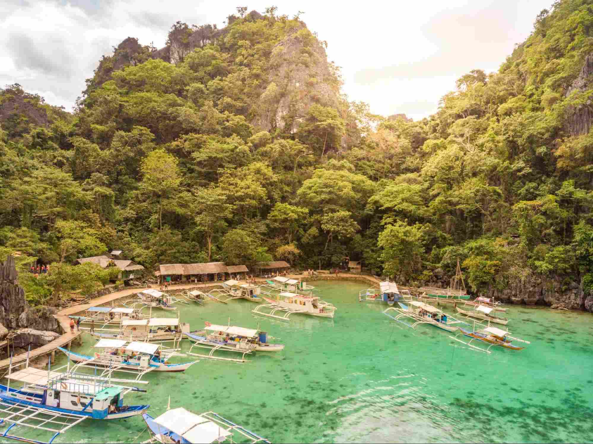 Blue crystal water in paradise Bay with boats on the wooden pier at Kayangan Lake in Coron island Blue crystal water in paradise Bay with boats on the wooden pier at Kayangan Lake in Coron island