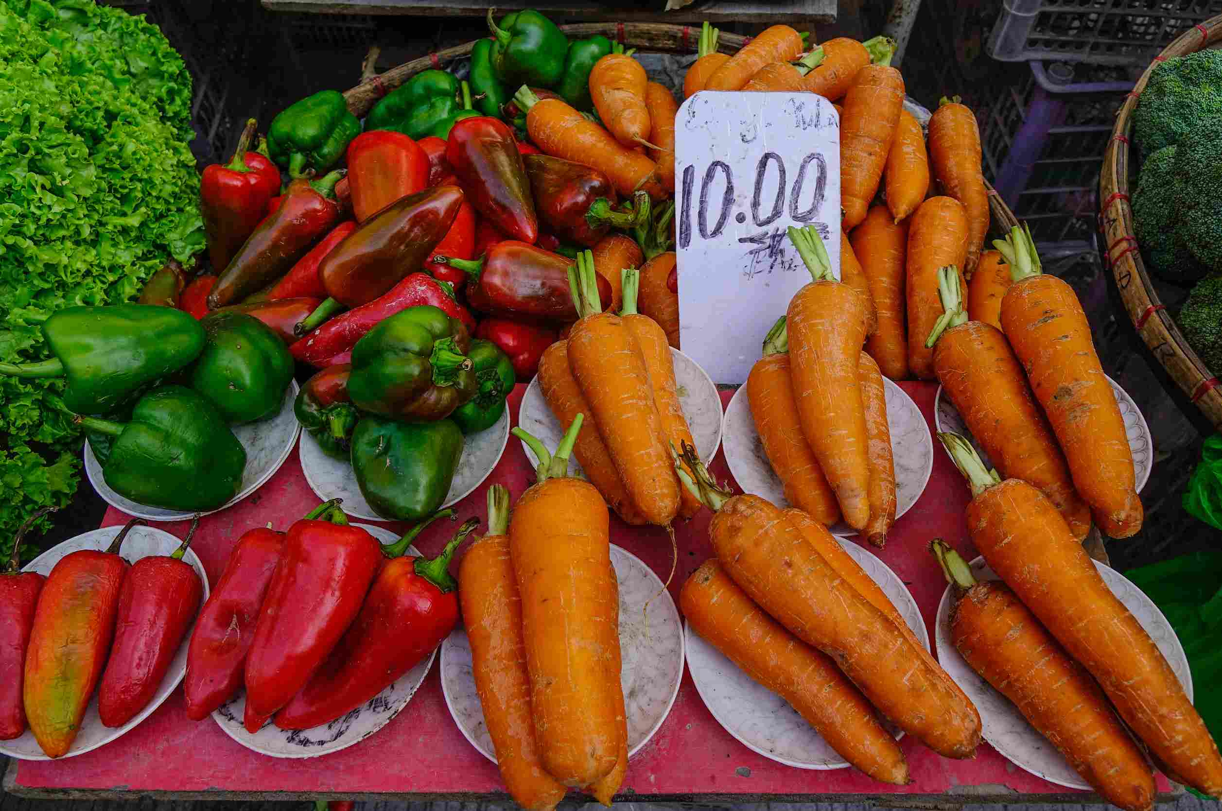 Customers buy fruits and vegetables in a street grocery shop in Manila