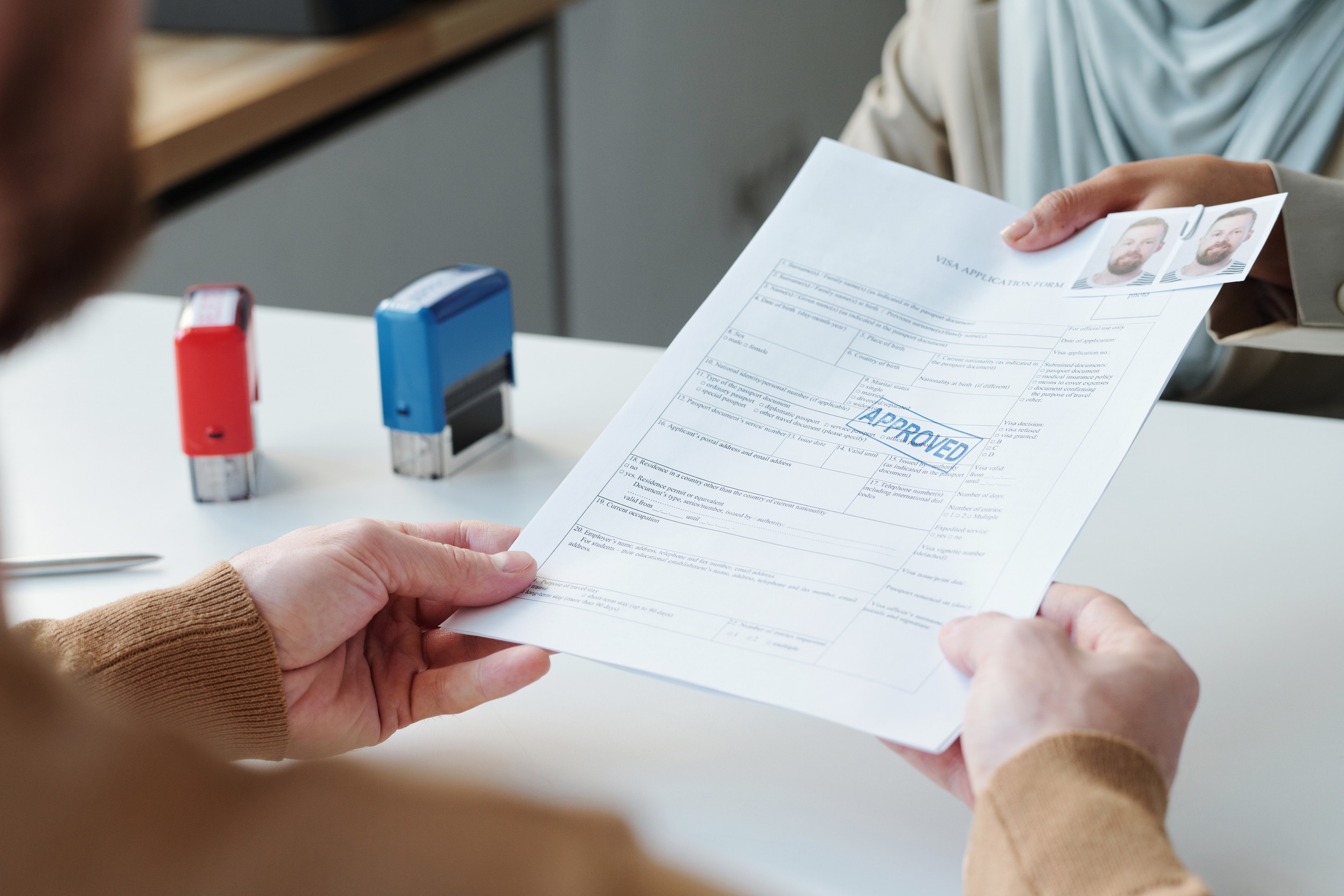 Unrecognizable muslim consular officer wearing hijab giving documents back to man after successful